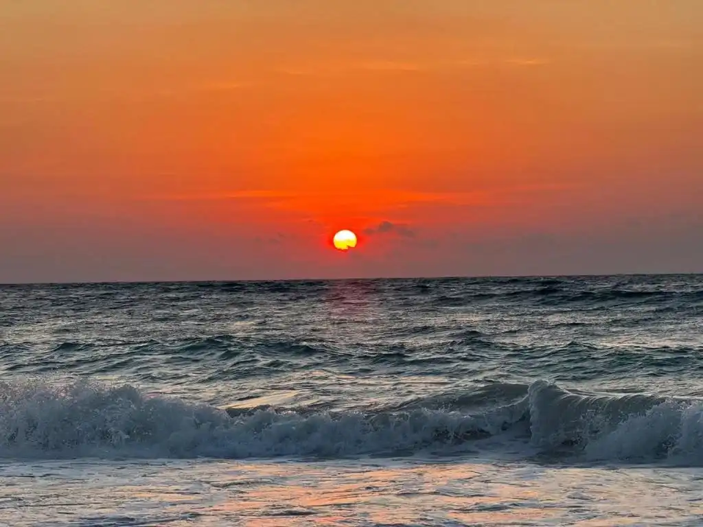 Amanecer anaranjado sobre las olas.