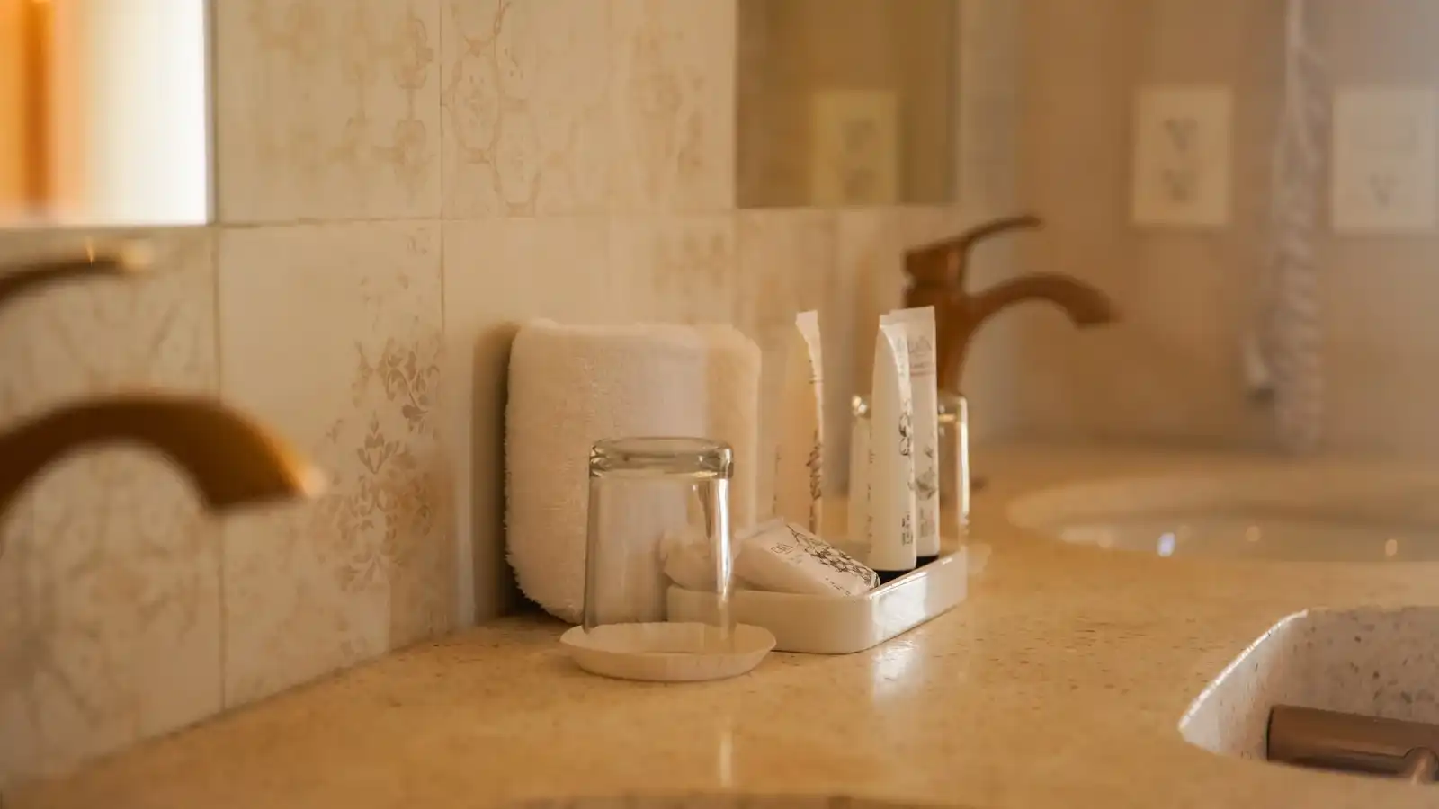 Detalle del lavabo: grifo de latón, vaso de cristal y jabón sobre la piedra.