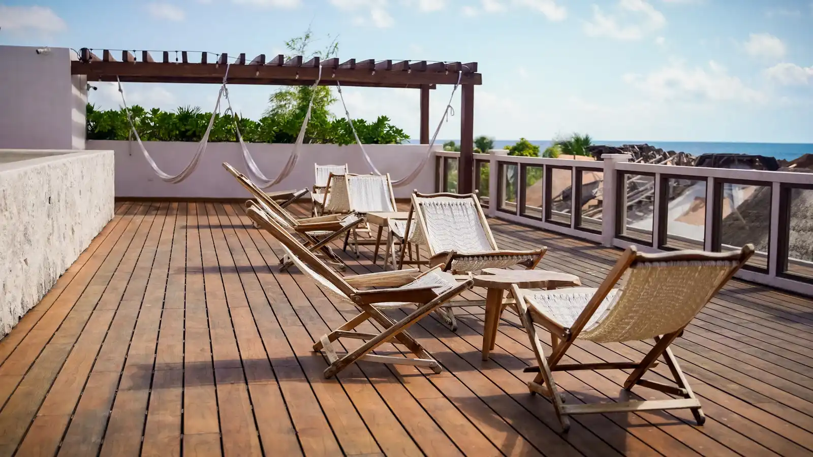 Terraza de madera en la azotea, con una hamaca colgada y dos sillas de tijera.