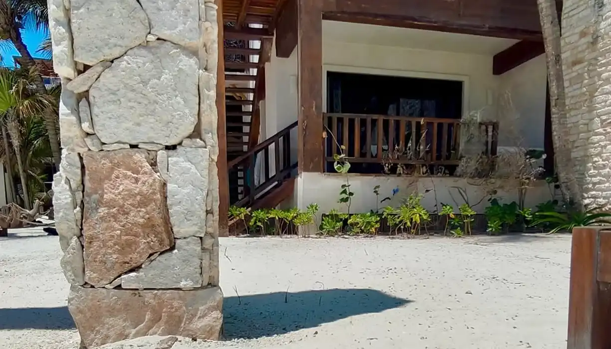Limestone passage down to the beach, with greenery on both sides and a wooden staircase at the end.