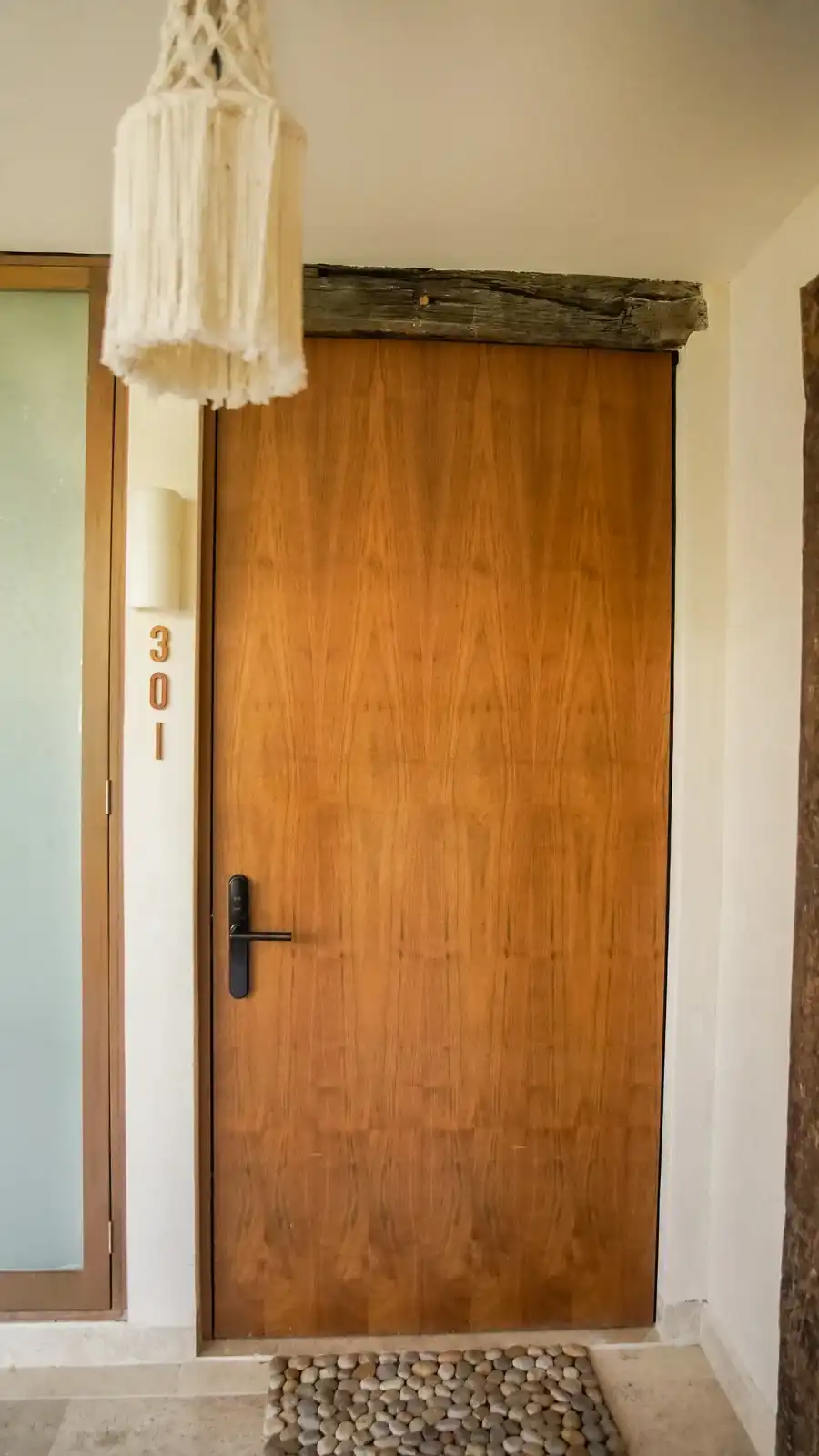 The wooden door of room 301, with a macramé hanging above it.