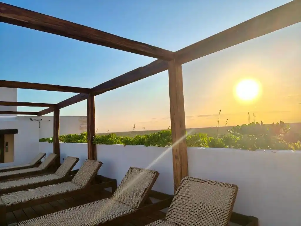 Loungers under a wooden pergola, at sunset.