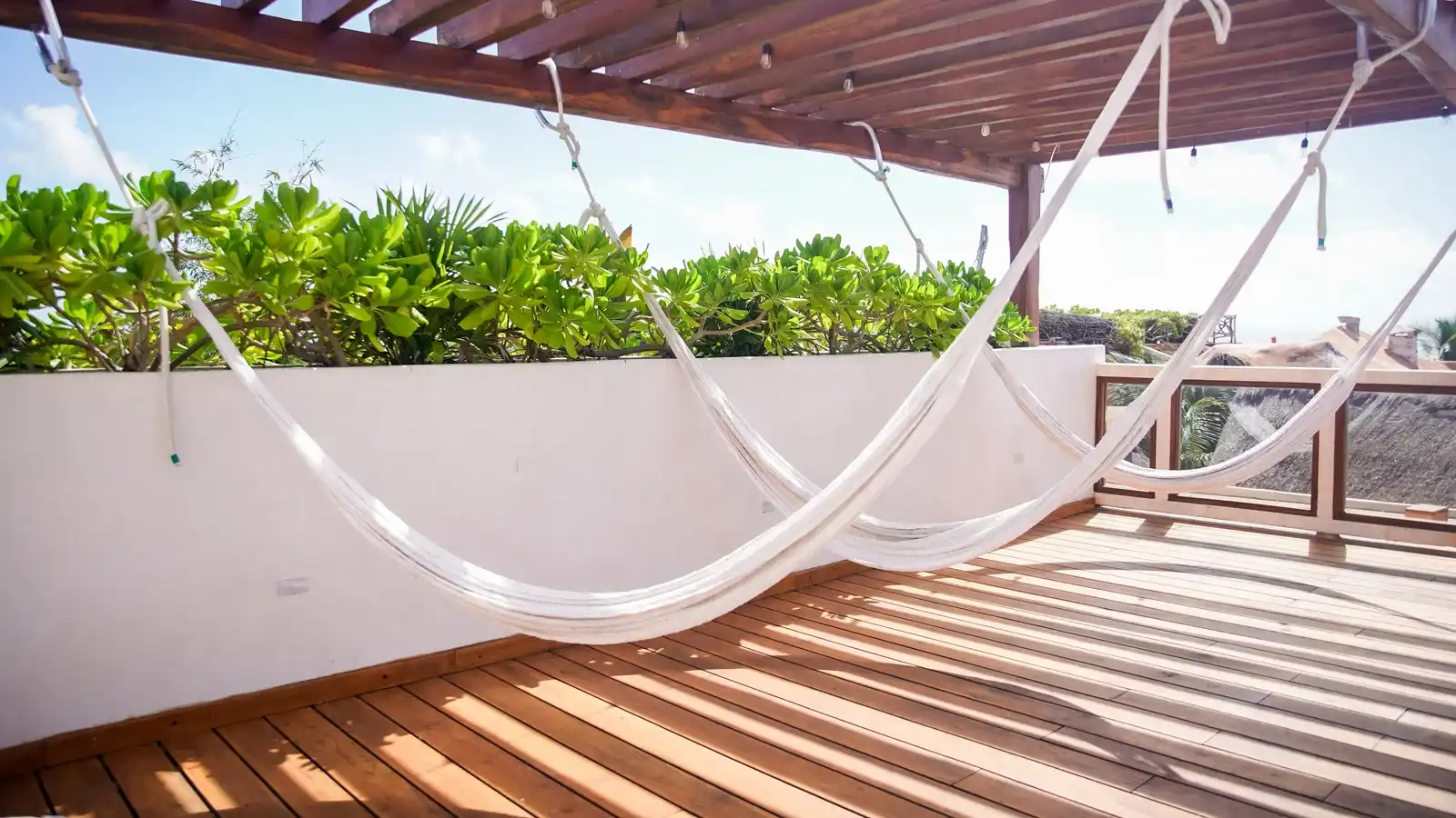 White hammocks hung under the rooftop pergola, above the wooden decking.