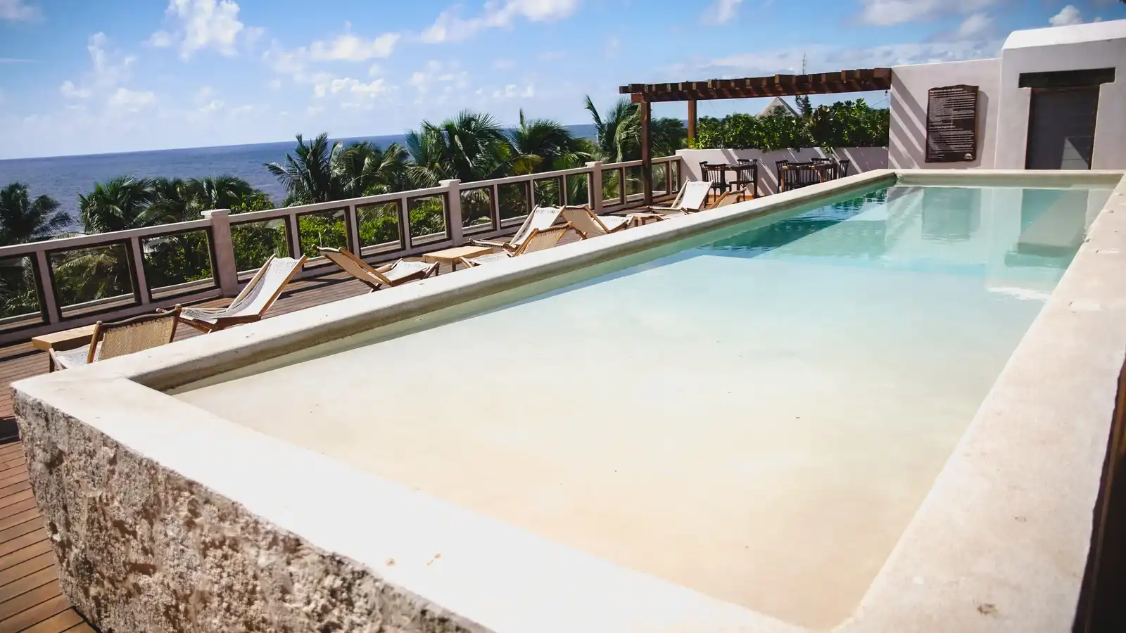The rooftop pool seen from one end, with the row of loungers and the sea horizon.