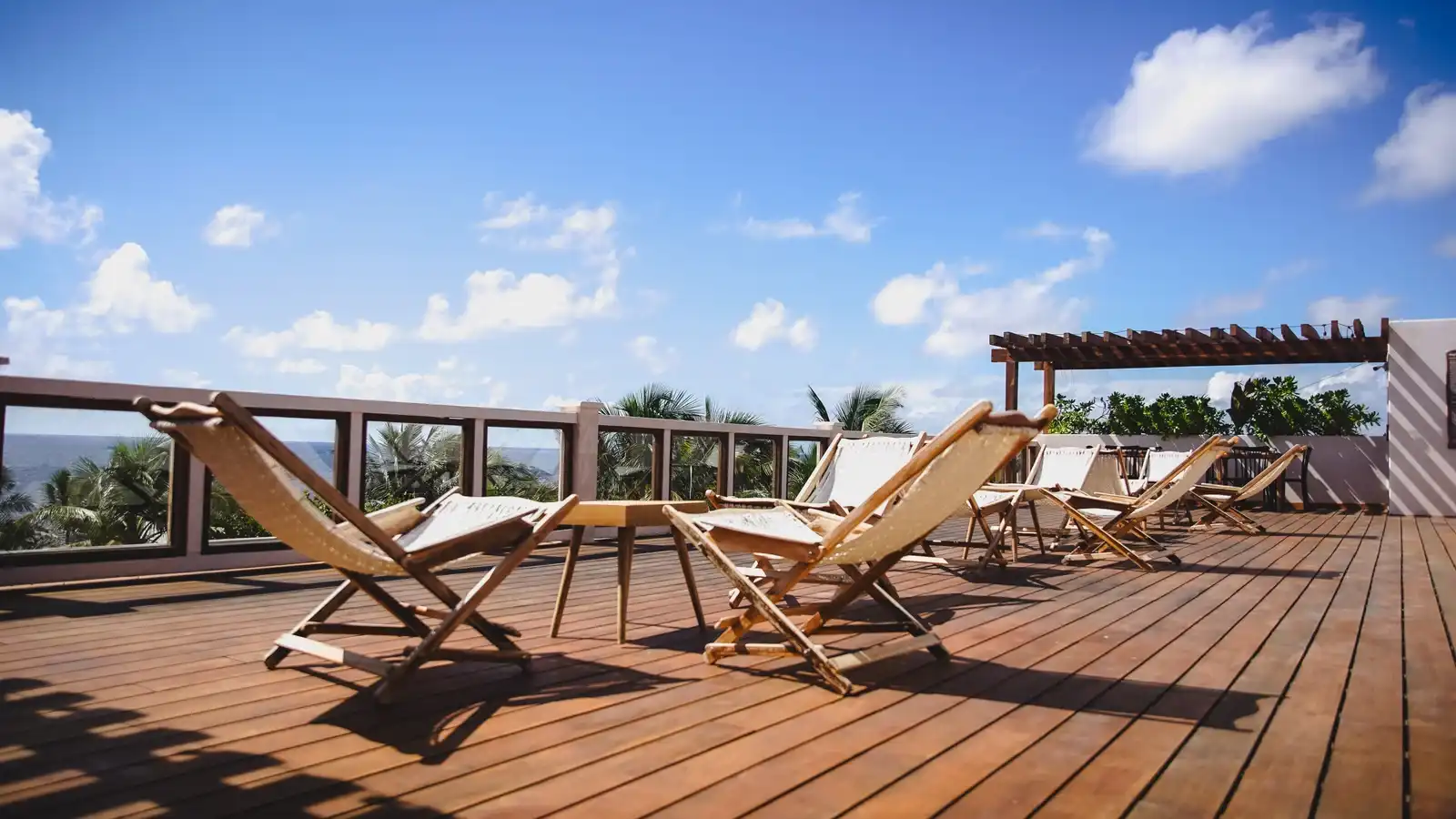Folding deckchairs on the rooftop decking, facing the railing and the sea.
