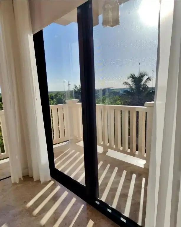 A curtain and window wall onto the balcony with its white balustrade.