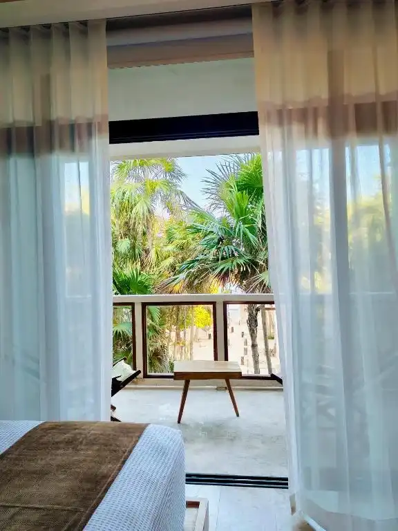 A bed beside the window wall, curtains open onto the balcony.