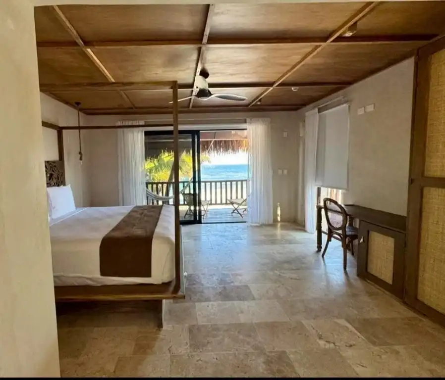 A room with a wooden ceiling and a way out to the balcony, the sea beyond.