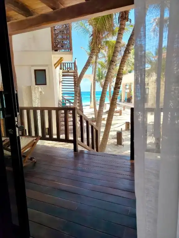 A wooden terrace with palms and the sea beyond.