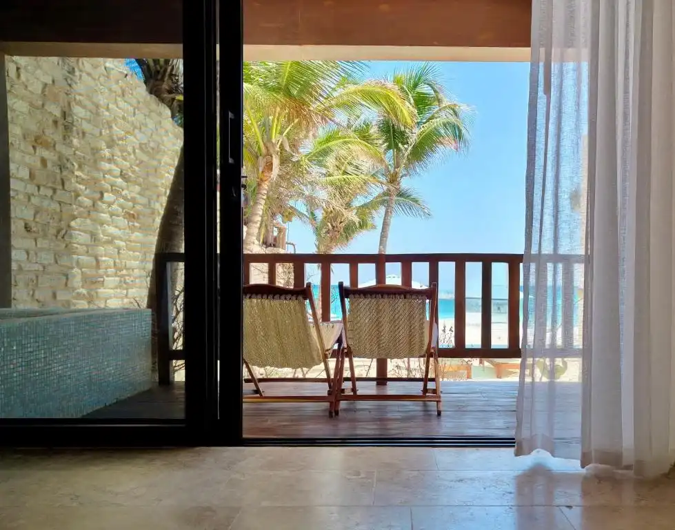 A balcony with two chairs and the palms, seen from the room.