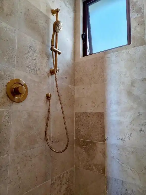 A brass shower, with a window onto the sea.