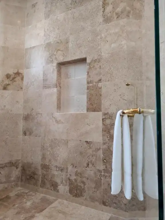 A shower with the towels hung on the stone wall.