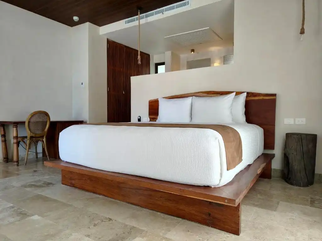 A room with a wooden bed and an armchair by the window.