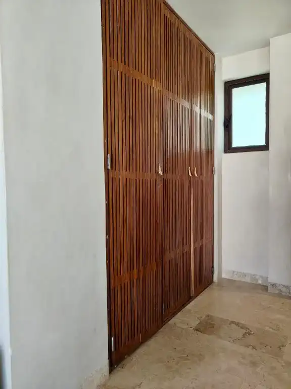 A closet with wooden doors, beside a window.