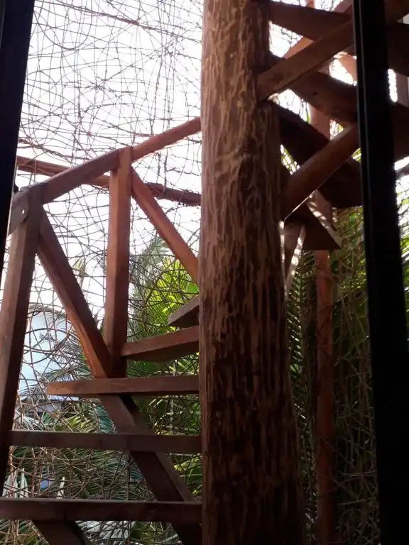 A wooden and log railing, with the garden greenery behind it.