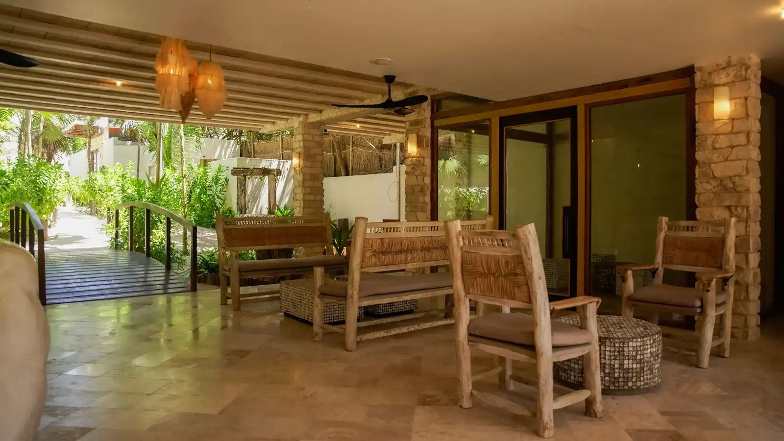 An open lounge with wooden benches and armchairs, beside the garden walkway.