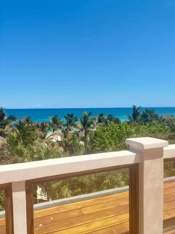 Decking with a railing, and the sea between the palm trees.