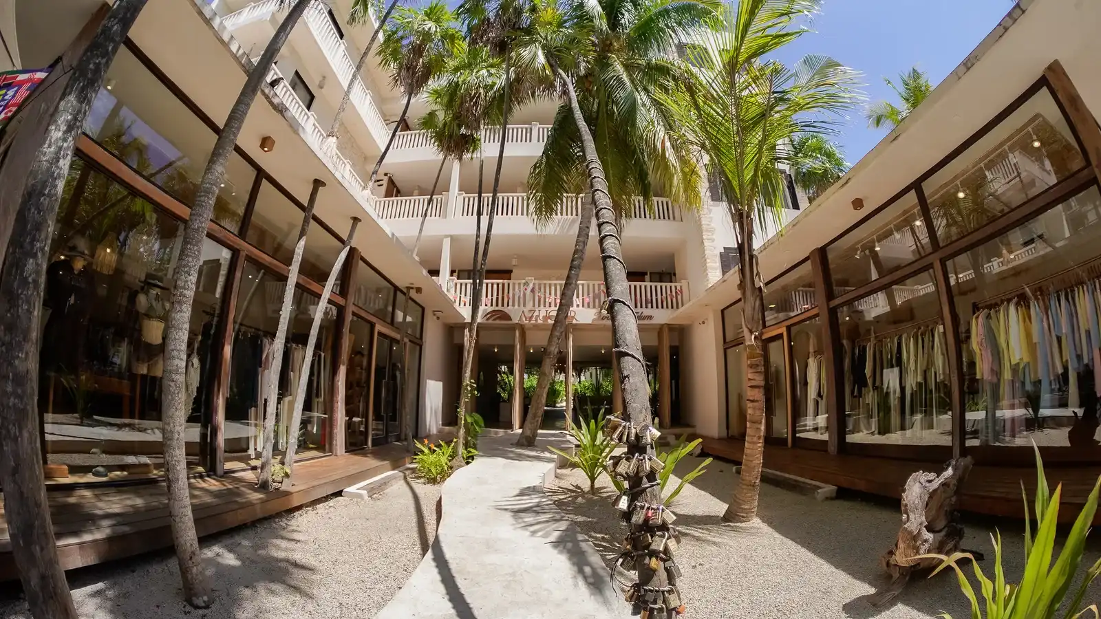 Patio interior entre los edificios, con palmeras altas y balcones de madera