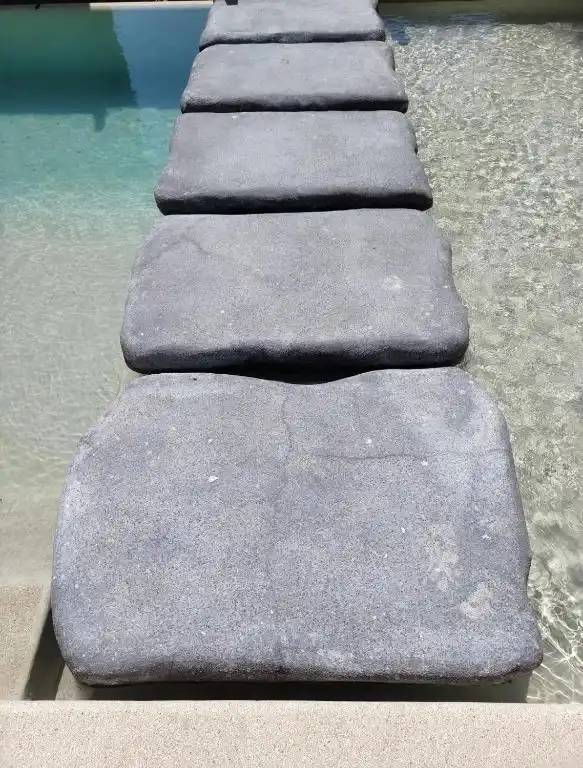 Stone stepping stones set into the water of the pool.