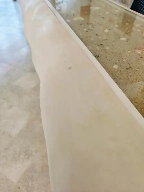 The edge of the pool, with sand and embedded shells.